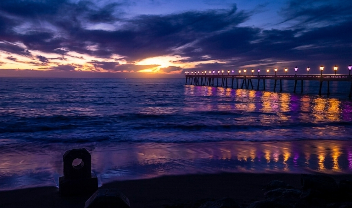 The Pacifica Pier at blue hour, lamp lights glowing gold and purple over the ocean